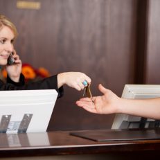 Young Receptionist giving room keys to customer at reception in hotel